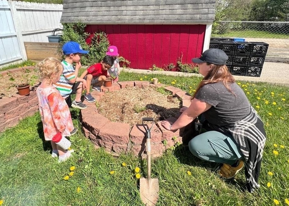 adult and 3 children planting in garden with native plants