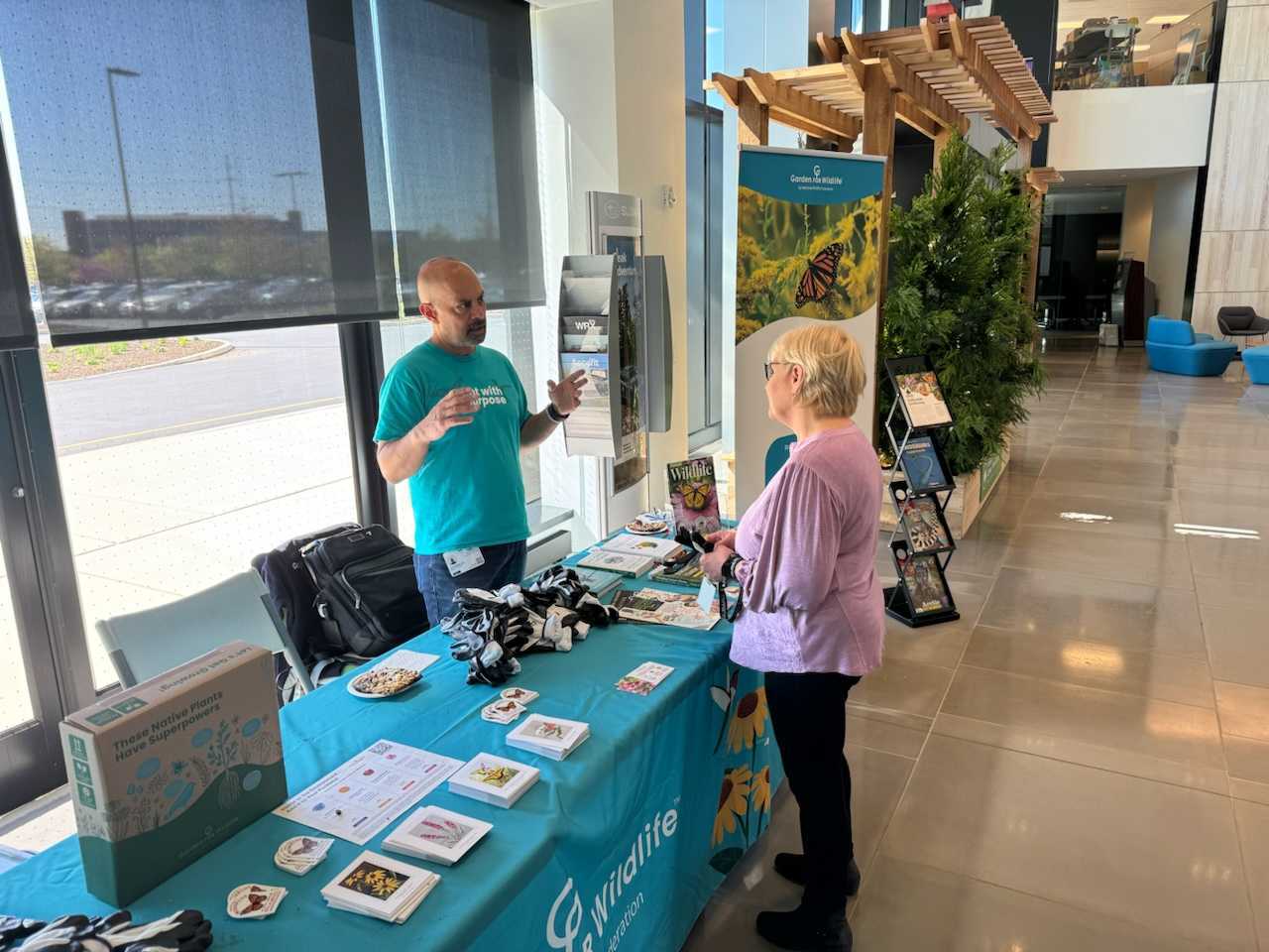 A man and woman talking at the Garden for Wildlife booth at a corporate event